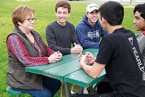 teacher sitting at table with students