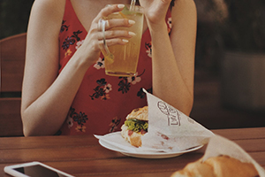 young woman eating sandwich on a croissant