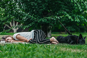 woman and dog lying in grass in park