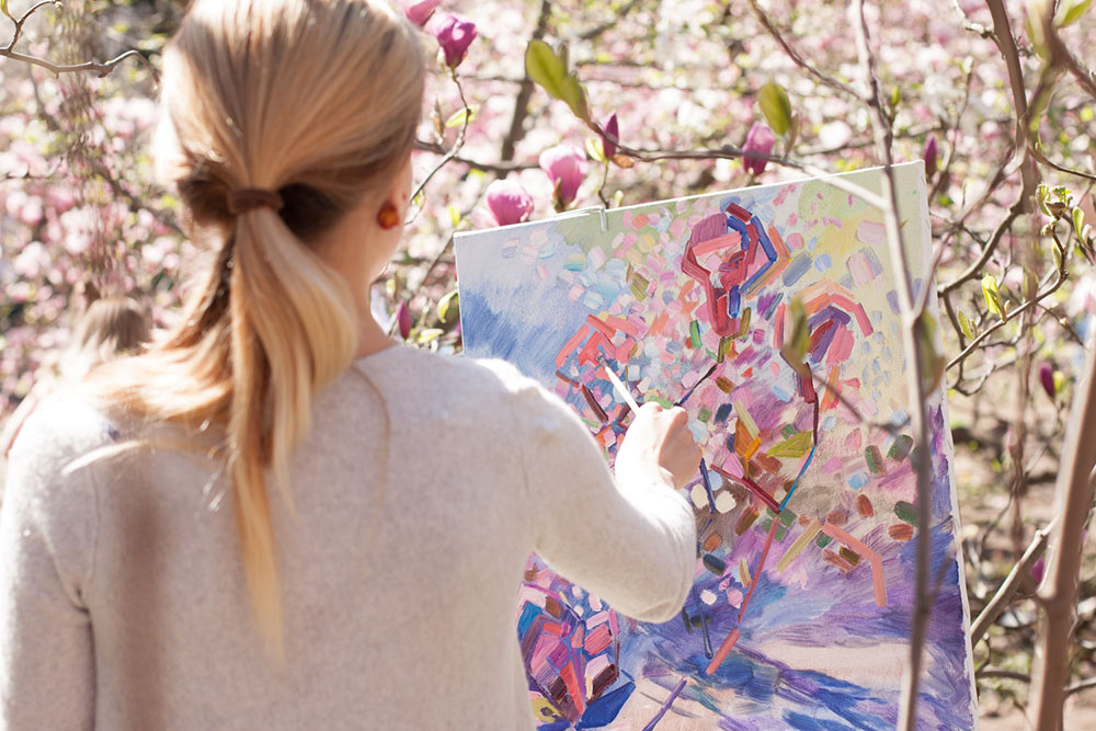 woman painting a grove of flowering trees