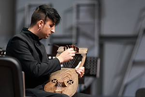 young man tuning a folk instrument