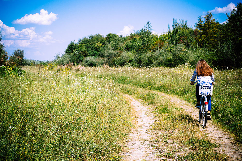 woman riding bike on dirt road in rural setting