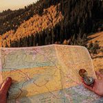 person holding map with mountains in background